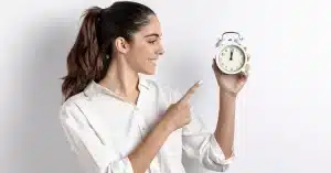 Imagem de uma mulher apontando um relógio em suas mãos representando que fazer uma boa administração do tempo vale a pena para quem trabalha em home office