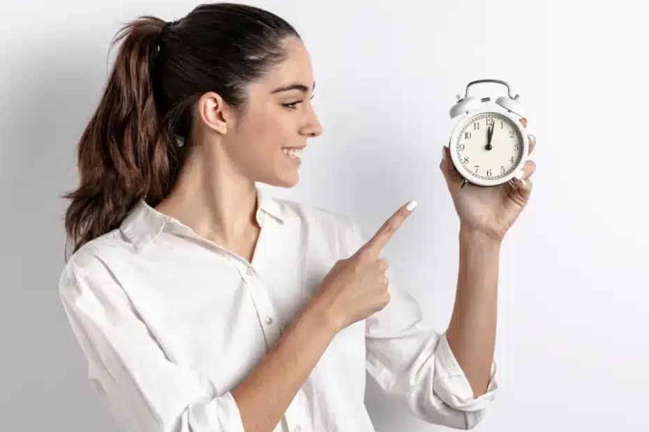 Imagem de uma mulher apontando um relógio em suas mãos representando que fazer uma boa administração do tempo vale a pena para quem trabalha em home office