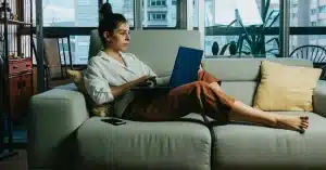 Imagem representando uma mulher no sofá com seu notebook aprendendo como fazer um planejamento de carreira
