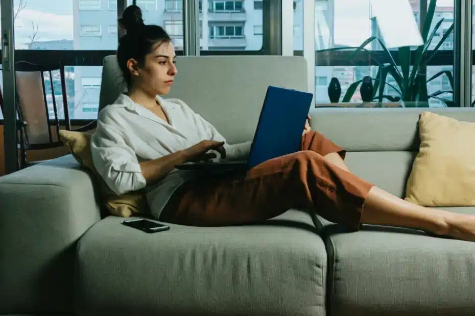 Imagem representando uma mulher no sofá com seu notebook aprendendo como fazer um planejamento de carreira