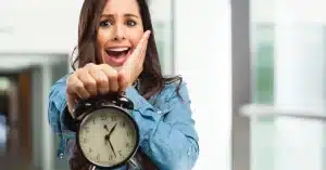 Imagem de uma mulher com um relógio nas mão direita e a mão esquerda na boca representando uma expressão de susto com o erros comuns no gerenciamento de tempo