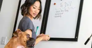 Imagem de uma mulher com seu cão anotando uma lista de tarefas para diminuir o estresse diário