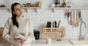 Imagem representando uma mulher refletindo em sua cozinha sobre como criar uma rotina de organização da casa para aumentar sua produtividade