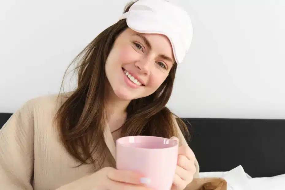 imagem de uma mulher sentada na cama com caneca para iniciar a rotina matinal de tim ferriss de produtividade