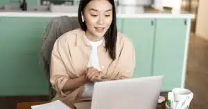 Imagem de uma mulher em home office em frente ao seu laptop com fones de ouvido aprendendo como criar conteúdo otimizado por voz e IA para ranquear no Google