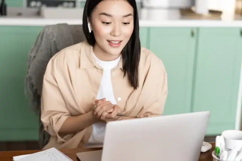 Imagem de uma mulher em home office em frente ao seu laptop com fones de ouvido aprendendo como criar conteúdo otimizado por voz e IA para ranquear no Google